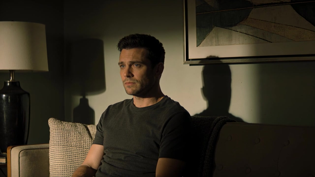 Reacting to lamp light, adult man in dark t-shirt turning head, shifting gaze on sofa