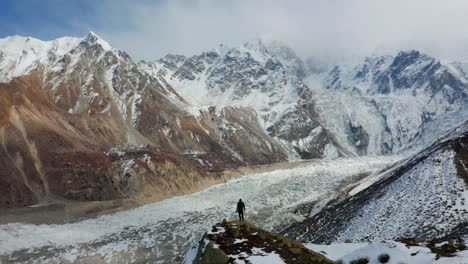 Mann-Steht-Oben-Auf-Der-Klippe-Mit-Blick-Auf-Den-Raikot-Gletscher-Und-Den-Nanga-Parbat-In-Gilgit-Baltistan,-Pakistan---Panoramaaufnahme-Aus-Der-Luft