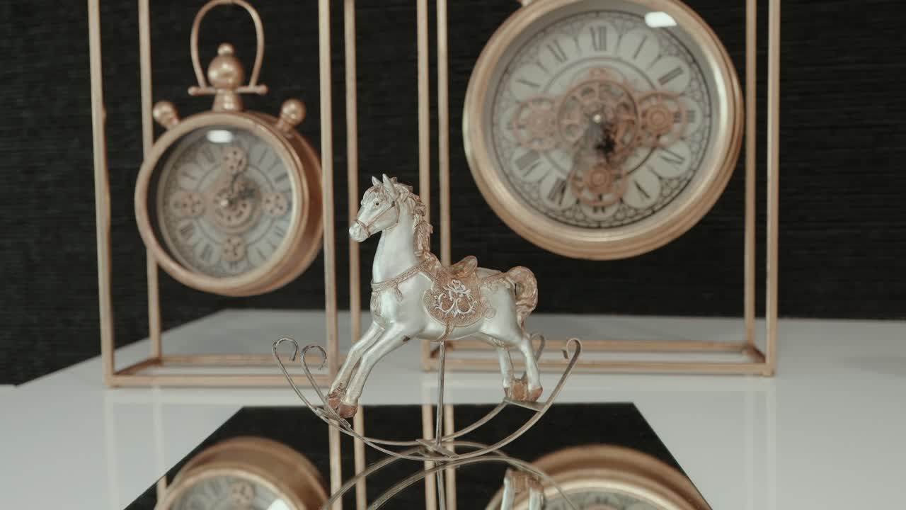 silver and gold rocking horse figurine in front of elegant vintage-style clocks