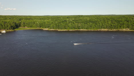 drone footage of a speed boat on the kennebec river in maine, high altitude, forward motion