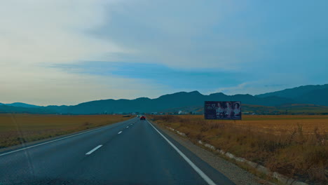 heading to the mountain range by the highway in valley. drive by the speedway after sunset.