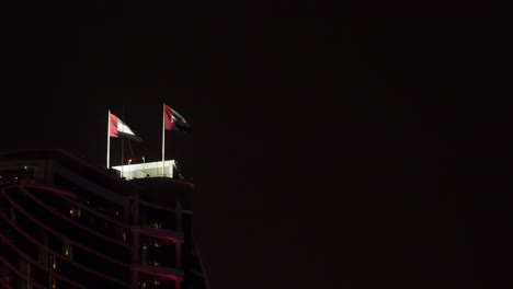 uae flags blowing in the wind on top of a building