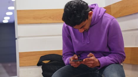 Young-man-hard-focused-on-smartphone-while-sitting-inside-office