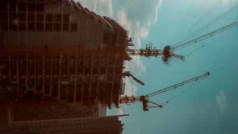 cranes lifting cement slabs onto a building at a construction site in abu dhabi united arab emirates vertical time lapse