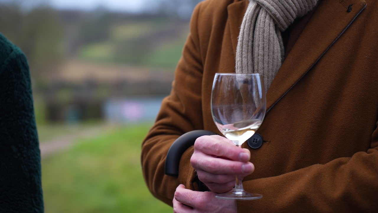 Persona con bicchiere di vino in una cantina belga.