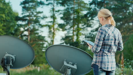 mujer sintoniza antenas parabólicas al aire libre utiliza tablet