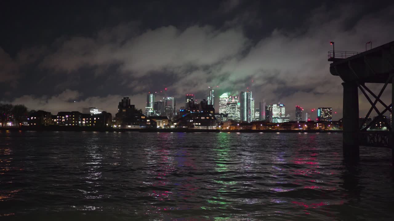 Canary Wharf view from Greenwich London across the Thames River at night near pier.