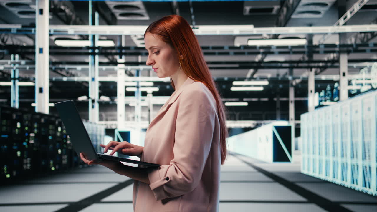 Woman Working on Laptop in a Modern Data Center