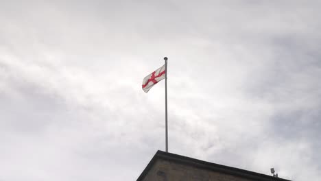 st georges flag waving in the window on top of a church on cloudy morning