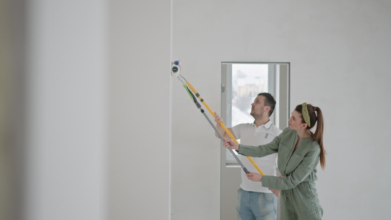 pareja pintando una pared en un nuevo hogar