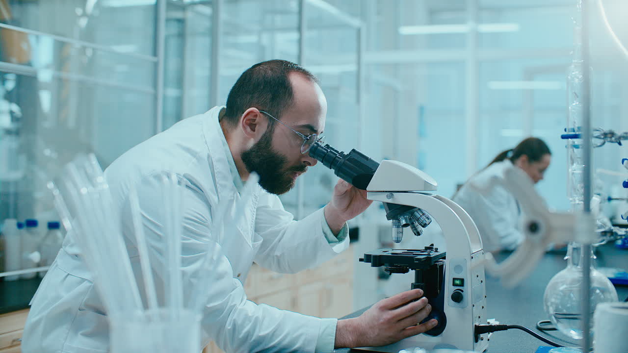 Scientist Analyzing Sample through Microscope in Laboratory