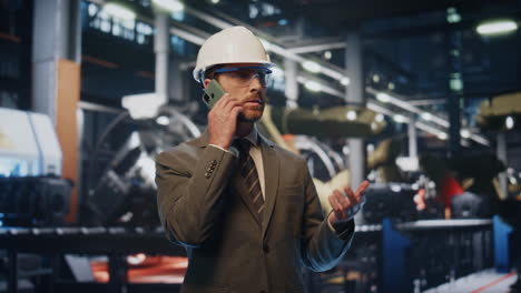 el dueño de la fábrica llamando al teléfono inteligente en la producción en casco de cerca.