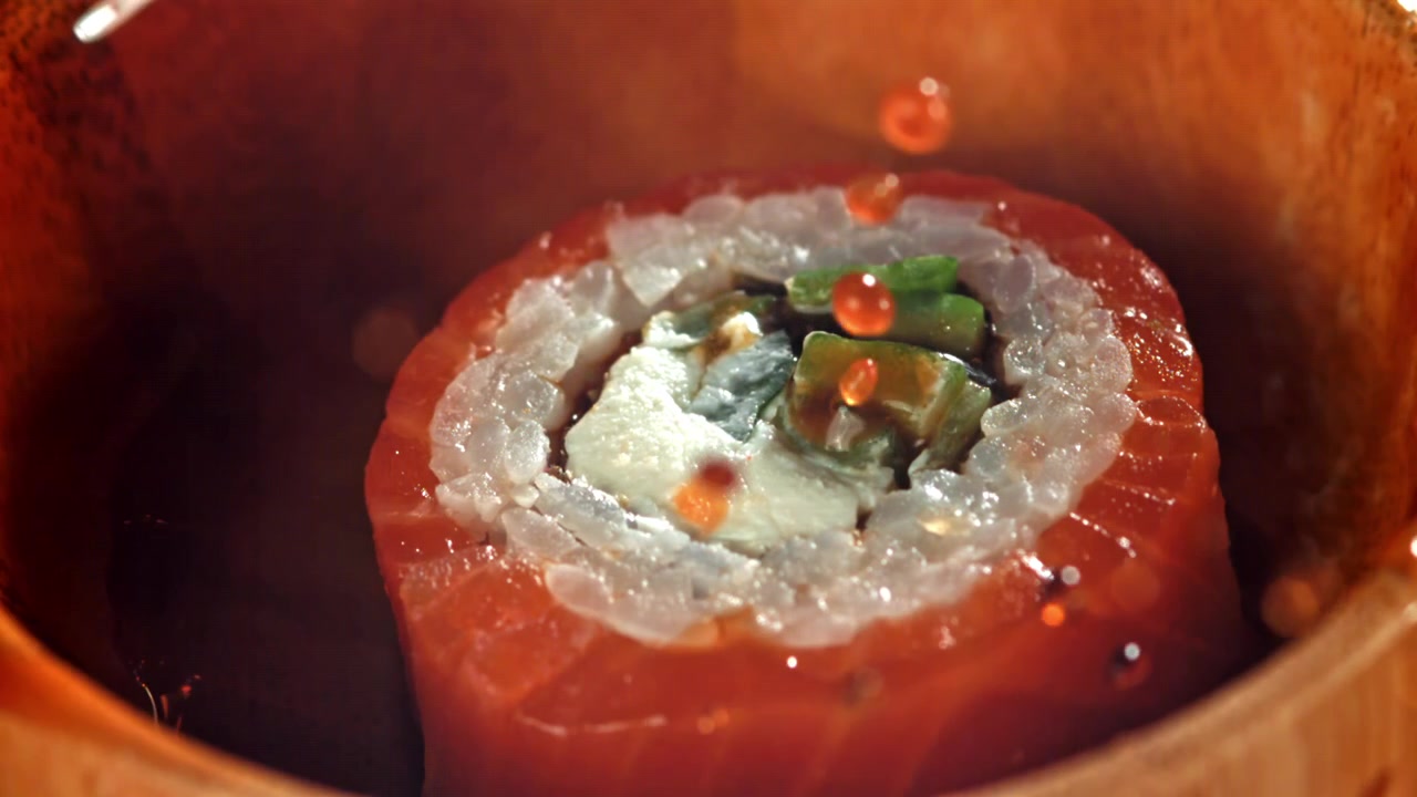 Sushi roll al salmone intinto nella salsa di soia e guarnito con uova di pesce