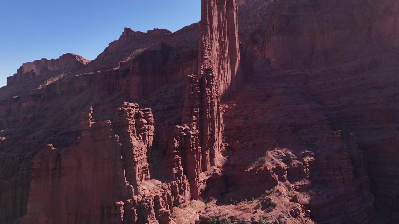 Drone che vola all'indietro allontanandosi dai pinnacoli rossi alle Fisher Towers a Moab, USA, in 4k