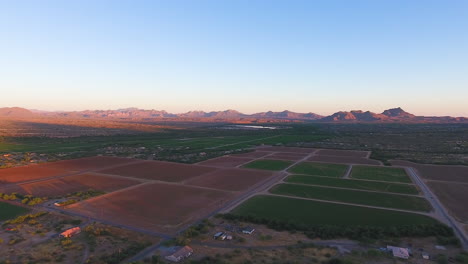 Panning-drone-shot-of-open-farm-fields-with-mountains-in-the-background-located-in-Flagstaff-Arizona