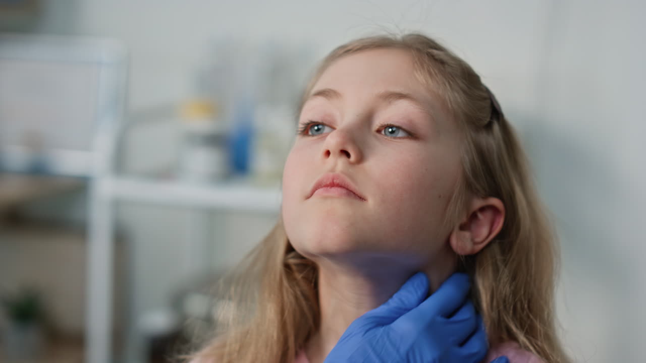 Closeup pediatrician checking throat after disease. Cute blond girl open mouth