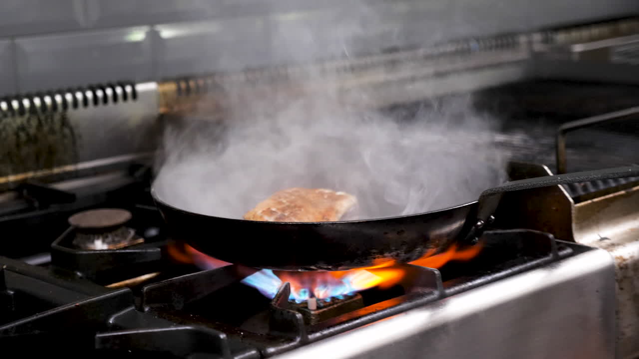 Duck breast being pan fried on a gas stove