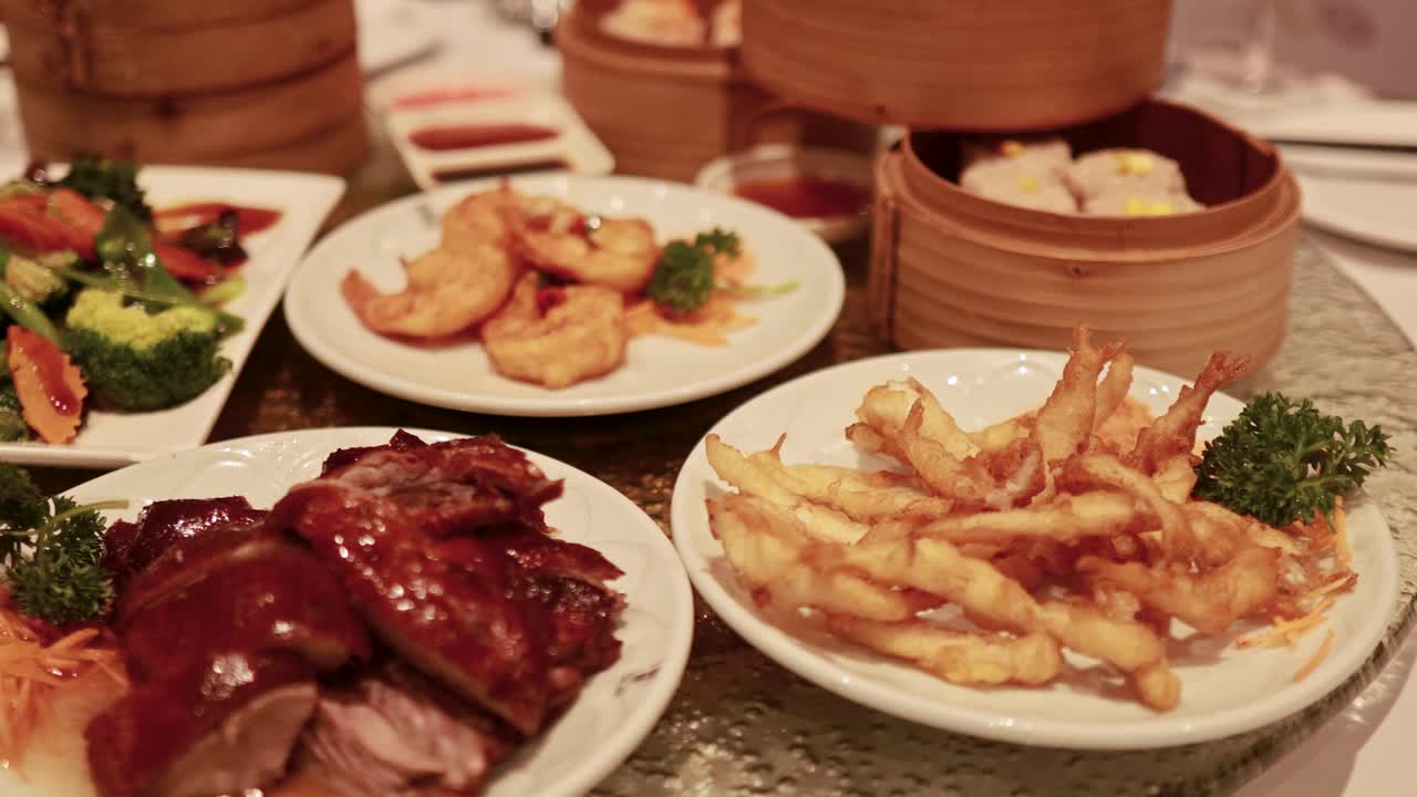 A variety of Chinese dishes and dim sum on a spinning glass table, captured in warm lighting
