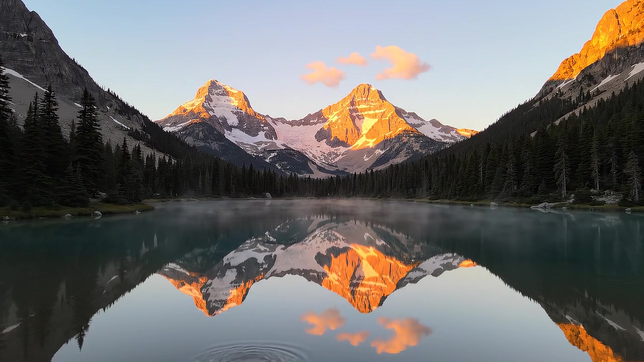 Majestic snow capped mountain peaks reflected in calm alpine lake