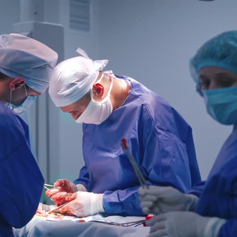 teamwork of surgeons in the operating room. group of doctors performing a surgery on patient. doctor's hands in sterile gloves with blood during surgery.