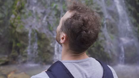 The-man-looking-around-in-front-of-the-waterfall.