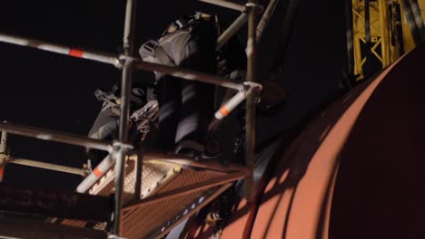 workers on scaffolding welding heavy steel equipment using chain blocks