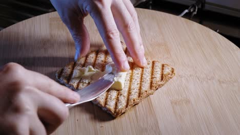 Hands Spread Melted Cheese On A Slice Of Whole Grain Toast