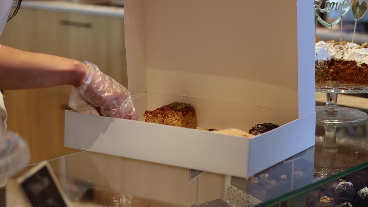 Confeiteiro colocando sobremesas em caixa de papel para viagem