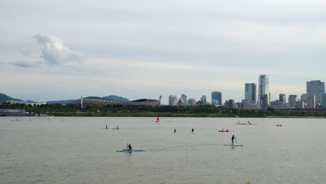 paddle boarding on river han with olympic stadium and trade tower in seoul, south korea