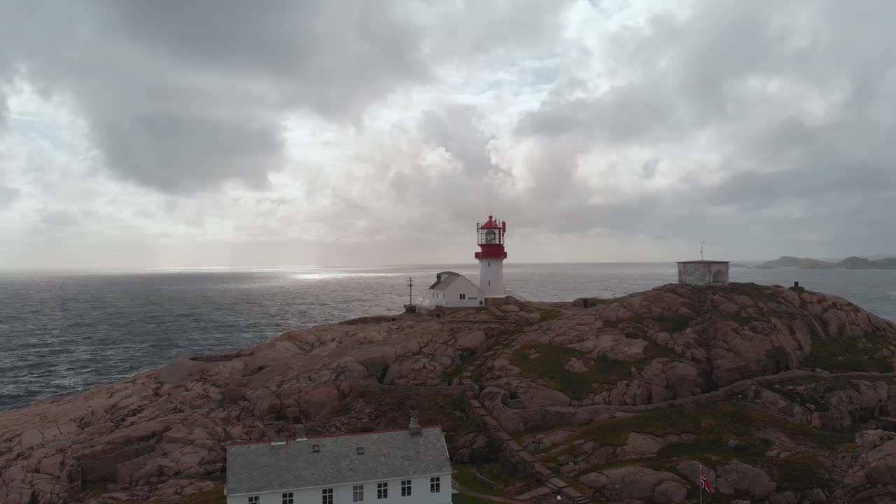 Lindesnes Lighthouse (Lindesnes fyr) Against Overcast Sky In Norway. Aerial Pullback Shot