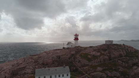 lindesnes lighthouse (lindesnes fyr) against overcast sky in norway. aerial pullback shot