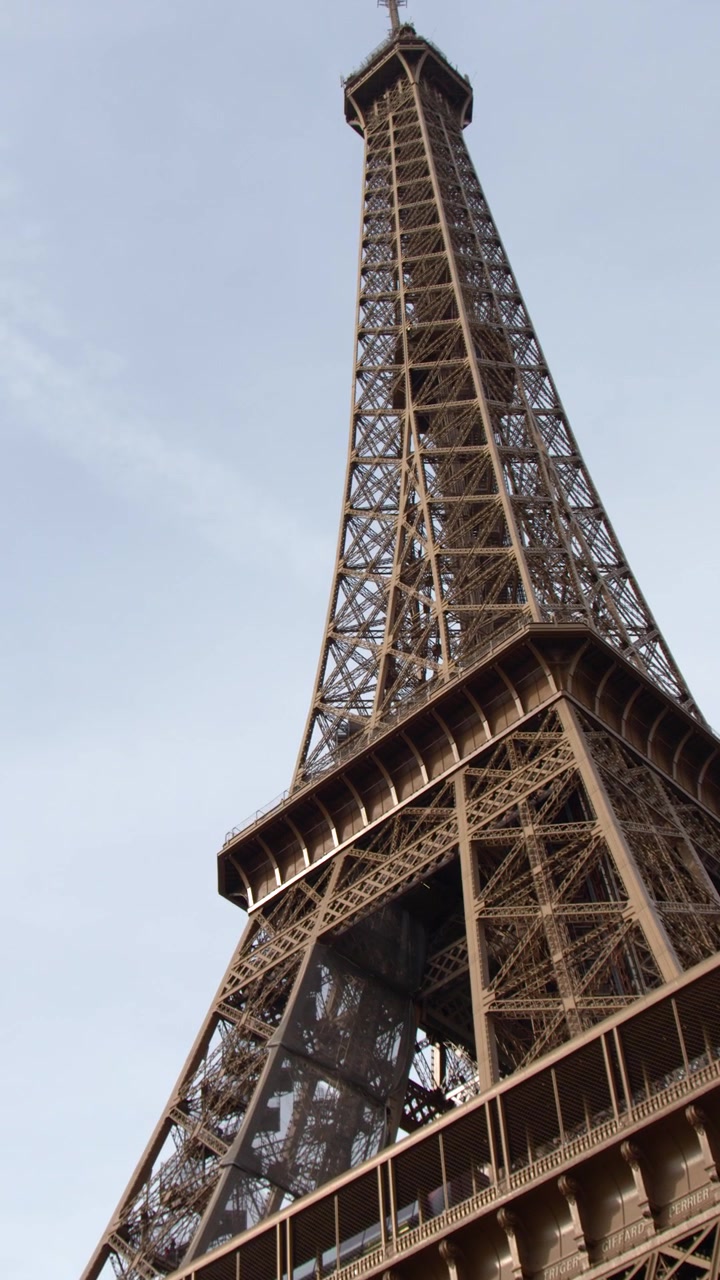Movimento della telecamera dal basso che si inclina verso l'alto lungo la storica struttura in ferro della Torre Eiffel