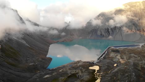 vista aérea del lago muttsee en glarus, suiza durante una puesta de sol nublada, con el embalse de la represa hidroeléctrica lleno de agua y paneles solares