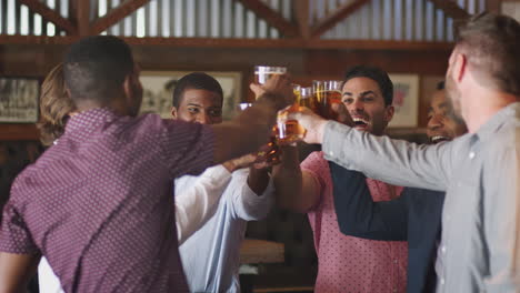 group of male friends on night out for bachelor party in bar making toast together