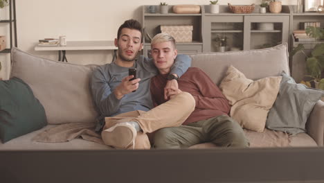 two young men sitting in hug and watching tv
