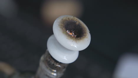 detail shot of cannabis being lit by a lighter inside a white bong bowl