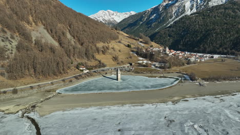 Drone-dolley-shot-of-the-sunken-church-of-Graun-on-a-frozen-lake-in-Italy