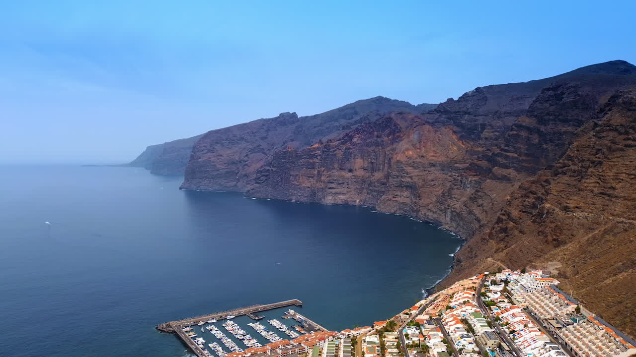 Footage over the urban area of Tenerife Island, Spain. Amazing rocks surrounded by the blue calm waterscape of the Atlantic Ocean. Aerial view