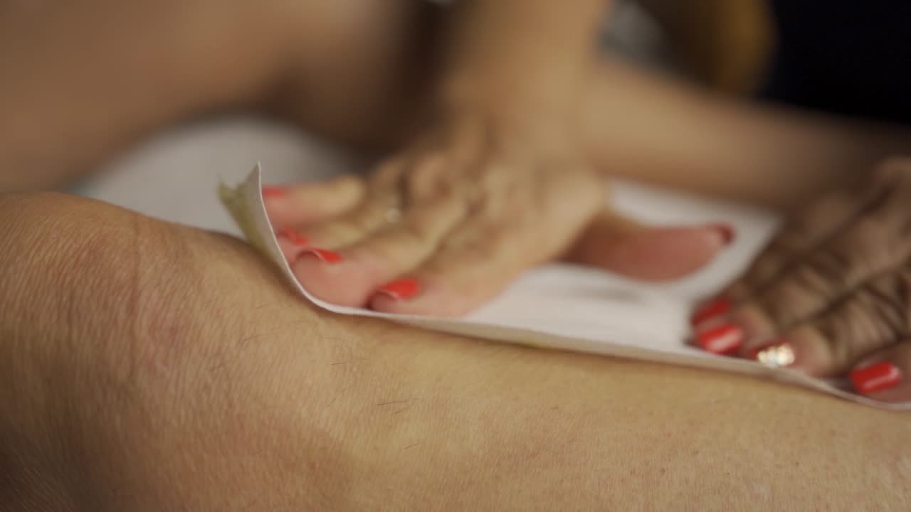 Primo piano: Depilazione con cera sulle gambe femminili al rallentatore.