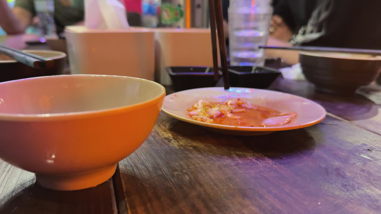 활기찬 호이안 저녁 식탁에서 젓가락으로 디핑 소스에 찍어 음식을 집는 모습. 캐주얼한 공동 식사, 따뜻한 레스토랑 분위기, 베트남 음식 문화의 솔직한 모습을 담고 있습니다.