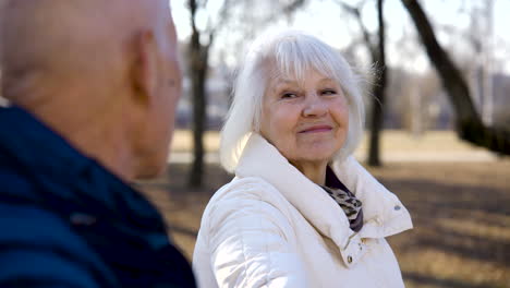 Close-up-view-of-a-senior-woman-talking-with-her-husband-in-the-park-on-a-winter-day
