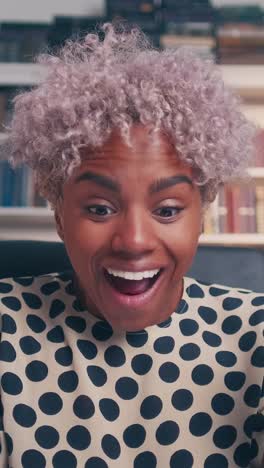 young enthusiastic overjoyed african american woman sits at table with laptop
