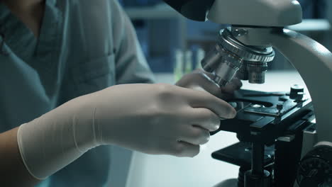 female lab scientist examining plant leaf with microscope