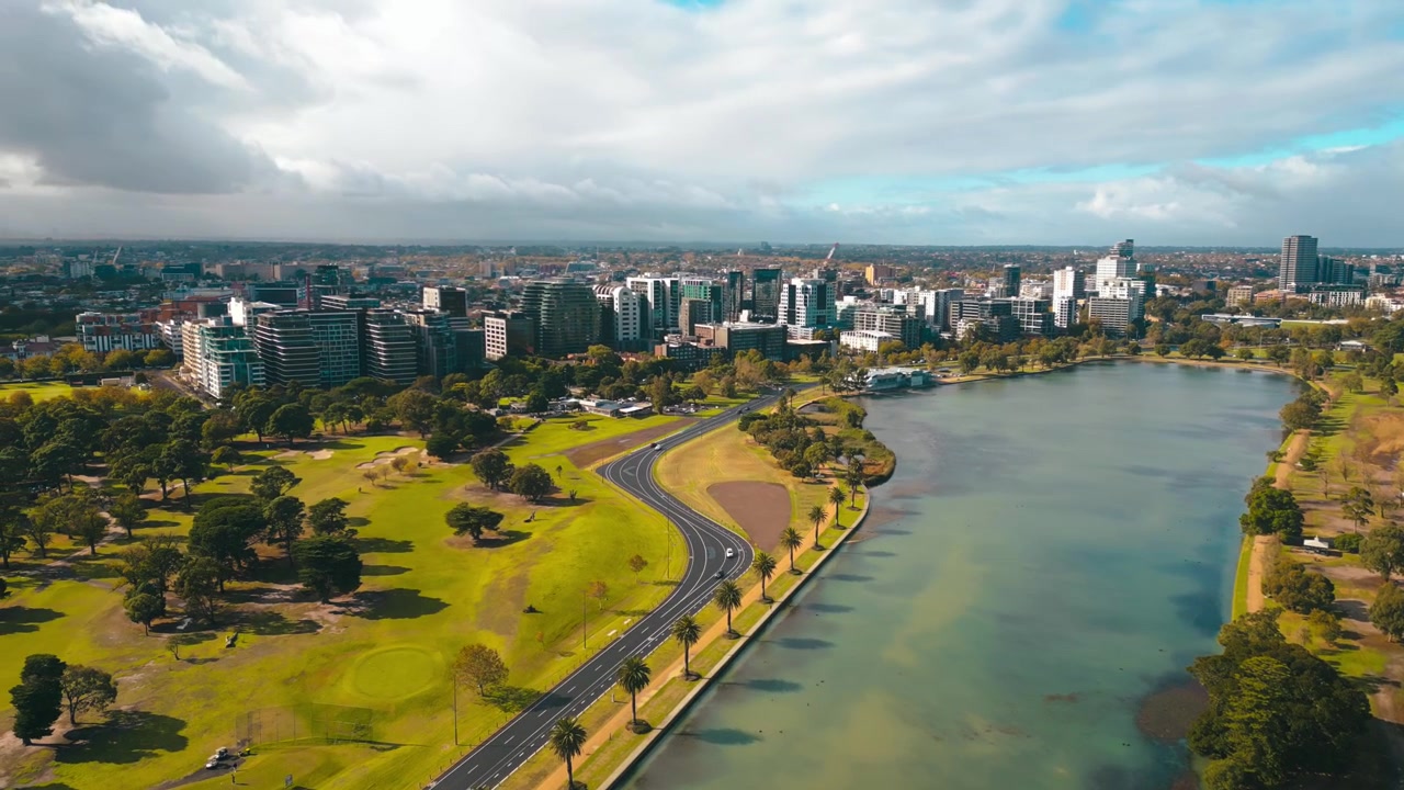 Riprese aeree del paesaggio di Albert Park, con lo Stadio Lakeside, paesaggio lacustre, alberi autunnali e cieli soleggiati.