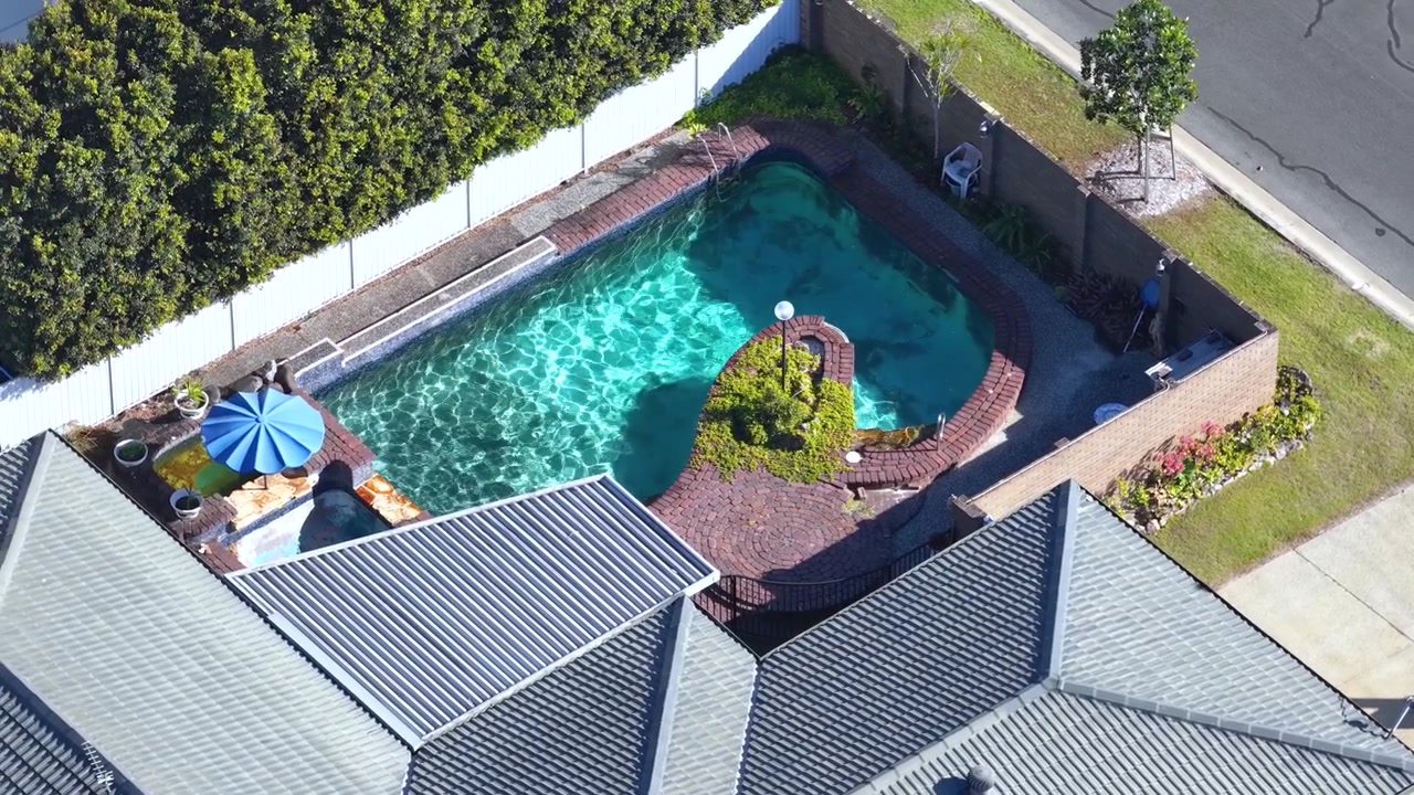High-angle drone shot of a backyard swimming pool and patio in Broadbeach Waters, Australia.