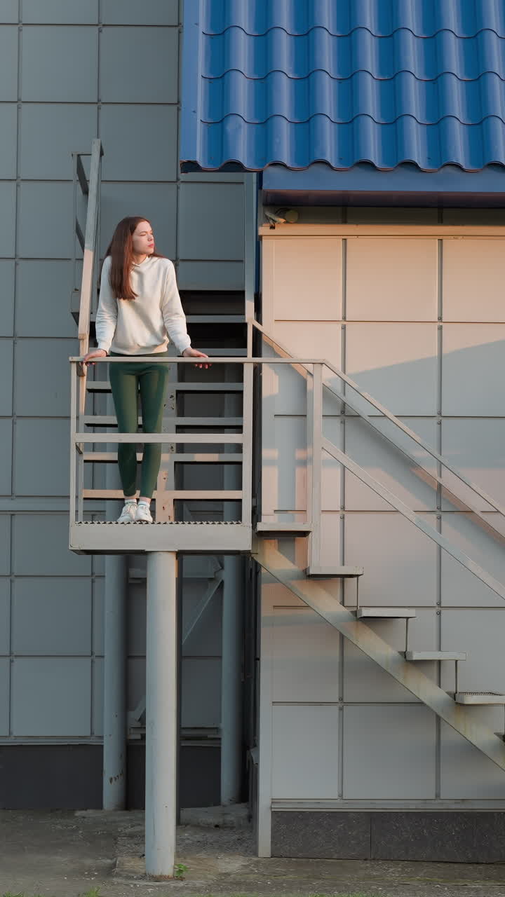 mujer de pie en las escaleras de un edificio. dama reflexiona sobre la depresión de pie sola en la altura. actitud negativa hacia la vida y atmósfera tranquila caminando al atardecer