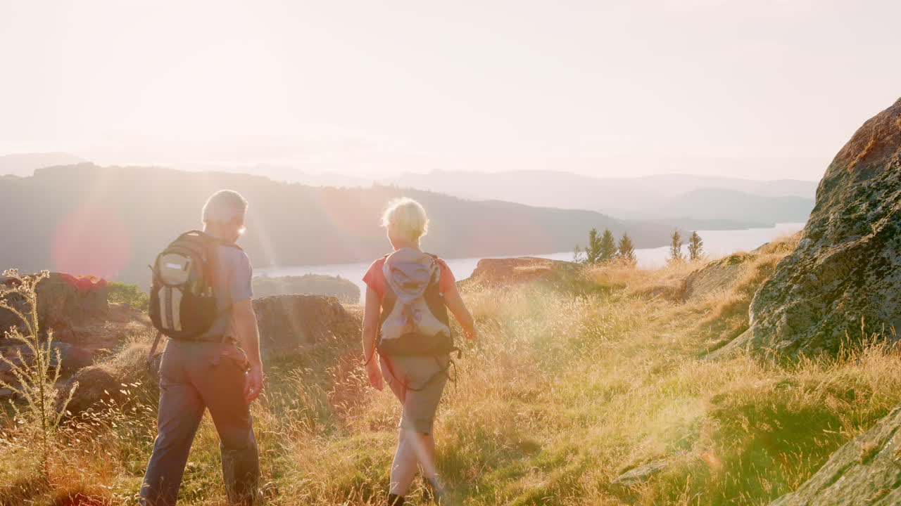 slowmotion-rückblick auf ein älteres paar, das auf einem hügel auf einer wanderung durch die wunderschöne landschaft im lake district in großbritannien spazieren geht