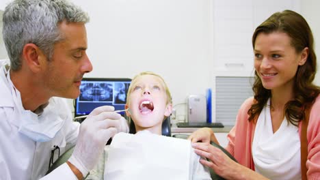 dentist examining young patient with dental tool