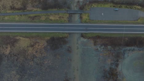 Aerial-establishing-view-of-high-water,-Durbe-river-flood,-brown-and-muddy-water,-agricultural-fields-under-the-water,-overcast-winter-day-with-light-snow,-birdseye-drone-shot-moving-forward