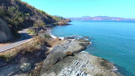 Aerial-view-following-the-coast-road-along-the-shores-of-Poto-Batu,-West-Sumbawa-Indonesia